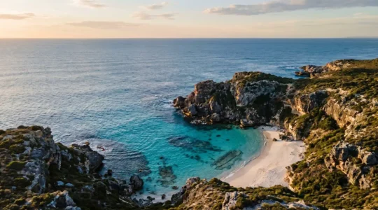 Vista aerea di una caletta nascosta con acque cristalline circondata da scogliere rocciose in una riserva marina protetta
