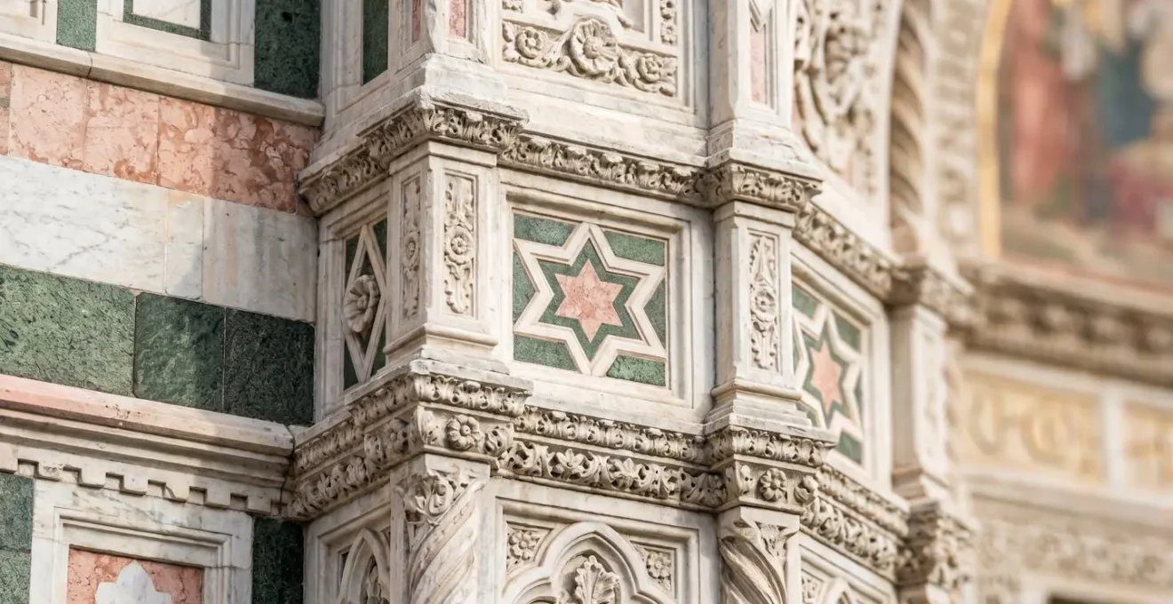 Primo piano ravvicinato della decorazione in marmi policromi sulla facciata del Duomo di Firenze con motivi geometrici rosa verde e bianco